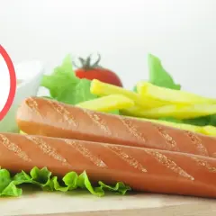 Czy pies może jeść parówki? Na zdjęciu piesek obok talerza z parówkami, frytkami i sałatą.